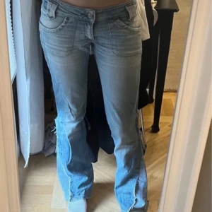 Ljusblå  bootcut jeans med slits - Säljer ett par ljusblå jeans från lee med bootcut passform och snygga slitsar nertill. Jeansen har låg midja, klassiska fickor fram och bak samt coola sömdetaljer längs benen. Perfekta för dig som gillar en avslappnad och trendig look. Lånade bilder från förra ägaren då dom inte passar🩷