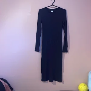 Svart långärmad marin blå från Lindex - Säljer en marin blå långklänning från Lindex med långärmad design och rund hals. Klänningen är ribbad upptill och har en slim passform som sitter snyggt mot kroppen. Perfekt för dig som gillar stilrena och enkla plagg med lite edge.