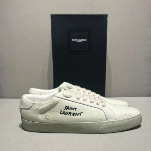 SPRILLANS nya Saint Laurent vita sneakers i canvas - Helt nya sneakers från Saint Laurent i creamy white färg. Självklart äkta äkthetsbevis finns😊 Allt og medföljer(box, dustbag, kort papper, och påsar) Som sagt helt nya och aldrig använda🙌. Pris kan diskuteras och vid snabbt köp blir det billigare🤝. Perfekta skorna nu till back to school👌
