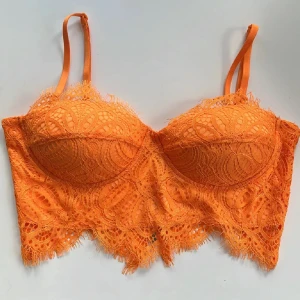 Orange spets korsett med dragkedja 🧡 - Snygg orange korsett med spetsdetaljer och justerbara axelband. Toppen har en croppad passform och vacker spetskant nertill. Baksidan har en dragkedja för enkel på- och avtagning. Aldrig använd! Storlek XS 🧡