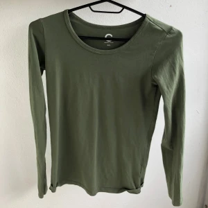 Mörkgrön långärmad bomullströja  - Enkel och mörkgrön långärmad tröja i bomull. Tröjan har rund halsringning och en smal passform. Den är XXS men är mer som XS