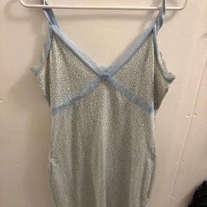 Ljusblå blommig kortklänning från H&M - Supersöt ljusblå kortklänning från H&M med små blommor och spetsdetaljer. Klänningen har smala axelband, v-ringning och en tight passform som framhäver figuren. Perfekt för sommarens alla tillfällen, med mjukt och stretchigt material.