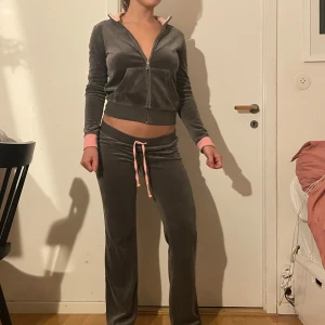 Grått Juicy Couture mjukis set - Säljer ett set från Juicy Couture  med låg midja och rosa snörning i midjan. Byxorna har en rak passform och är perfekta för en chill och avslappnad look. Väldigt fint och unikt. PS, står juicy stort på baksidan av fleecen❤️☺️🫰