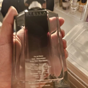 Stella McCartney Eau de Parfum 100 ml - Säljer en elegant parfym från Stella McCartney. Flaskan är sexkantig med svart och silverfärgat lock och har en snygg mörklila ton i glaset. Perfekt för dig som gillar stilrena och moderna dofter i en lyxig förpackning.VINTAGE