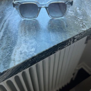 Gråa solglasögon från Chimi - Snygga gråa solglasögon från Chimi med fyrkantig form och mörka linser modell 04. Perfekta för en stilren look. Kommer med ett praktiskt fodral.