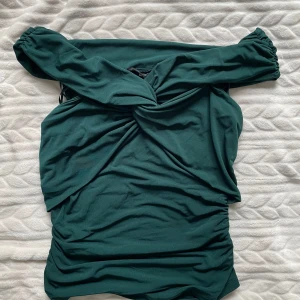 Grön omlott top från BikBok - Snygg grön tio från BikBok i storlek M. Klänningen har en elegant drapering och långa ärmar. Perfekt för en stilren look.