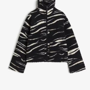 Svart och vit teddy jacka med zebramönster - Säljer en slutsåld och eftertraktad teddy jacka med zebramönster. Jackan har en dragkedja framtill och hög krage för extra värme. Perfekt för kyliga dagar när du vill sticka ut lite extra. 🖤🤍