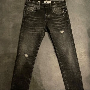Snygga jeans från Replay - Svarta jeans från Replay med snygga slitna detaljer. Modell willbi sitter som anbass. Size 29/30, Nyskick!