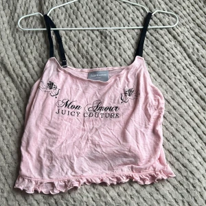 Rosa linnetopp från Juicy Couture - Säljer en söt rosa linnetopp från Juicy Couture med texten 'Mon Amour' och 'Sleeping Angel'. Toppen har svarta axelband och volangdetaljer vid nederkanten. Perfekt för en avslappnad stil.