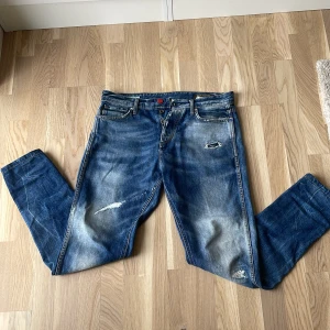 Blå ripped jeans från Jack & Jones - Säljer ett par snygga blå jeans från Jack & Jones med slitna detaljer. Jeansen är använt 2-3 gånger och är i väldigt bra skick. Pris kan diskuteras!