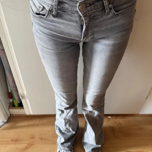Grå jeansbyxor - Snygga grå jeansbyxor med låg midja och bootcut-stil. De har en klassisk femficksdesign och stängs med dragkedja och knapp. Perfekta för en avslappnad look.