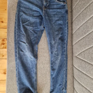 Blå jeans från Jack & Jones - Snygga blå jeans från Jack & Jones med klassisk femficksdesign och en läderpatch med logotyp baktill. Perfekta för en avslappnad stil.