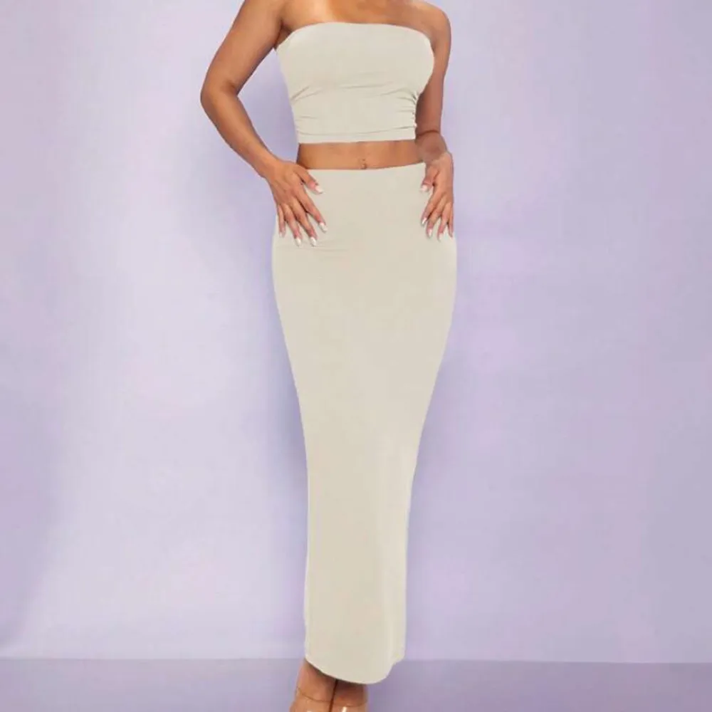 Snygg beige set med en tight passform. Toppen är croppad och kjolen är lång, vilket ger en elegant look. Perfekt för en stilren och modern outfit.. Mekot.