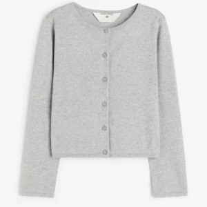 Grå kofta från H&M - Säljer en stilren grå kofta från H&M. Den har långa ärmar och knappar framtill. Perfekt för en avslappnad look.🥰🥰