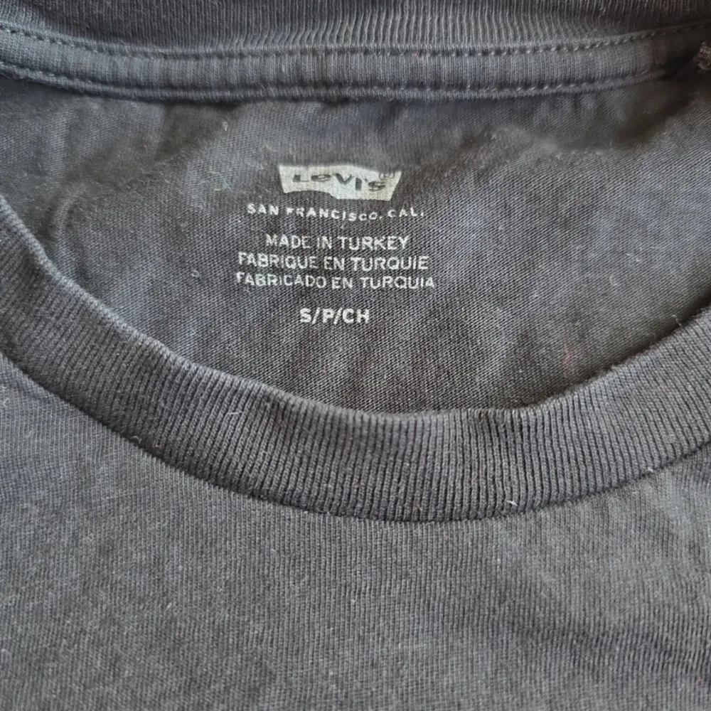 Säljer en svart t-shirt från Levi's med deras ikoniska röda logga på bröstet. T-shirten är kortärmad och gjord i mjuk bomull. Perfekt för en avslappnad stil. Passar bra till jeans eller shorts!. T-paidat.