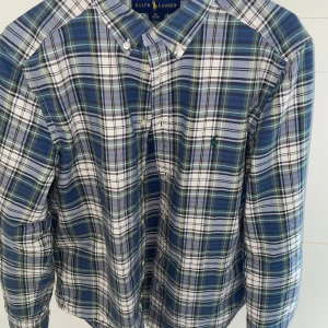 Ralph lauren skjorta  - Säljer en snygg flanellrutig raffeskjorta  i den amerikanska storlek 18-20 år vilket motsvarar small/medium i svensk storlek. Den är knappt använd och har inga defekter eller fläckar, som nyskick. Priset är ej hugget i sten så kom gärna med förslag.
