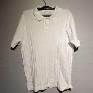 Vit pikétröja från KappAhl  - Säljer en stilren vit pikétröja från KappAhl. Tröjan har korta ärmar och en klassisk krage med knappar. Perfekt för en avslappnad men ändå snygg look. Passar bra till både jeans och chinos.