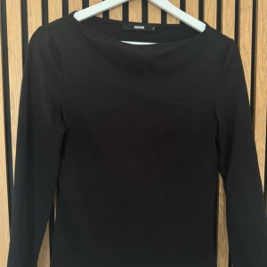 Svart långärmad topp från Bik Bok - En stilren svart långärmad topp från Bik Bok med rund halsringning. Enkel och klassisk modell som passar till mycket. Mjukt material och figurnära passform. Med slits vid ärmarna. 