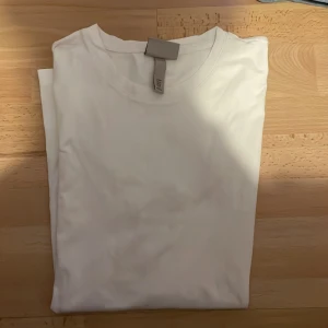 Vit slim fit t-shirt från H&M - Säljer en klassisk vit slim fit t-shirt från H&M. Perfekt basplagg med rund halsringning och mjukt material. Enkel och stilren design som passar till det mesta. Skön att bära och lätt att matcha med andra plagg.