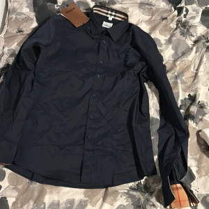 Mörkblå skjorta från Burberry - Snygg mörkblå skjorta från Burberry som passar Suveränt under sommaren Storlek L som samt passar  M