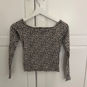 Leopardmönstrad långärmad topp - Säljer en snygg långärmad topp med leopardmönster i svart och beige. Toppen har en tight passform och rundad halsringning. Från Gina tricot 