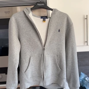 Grå hoodie från Polo Ralph Lauren - Säljer en klassisk Ralph Lauren hoodie som är i storlek L i barnstorlek