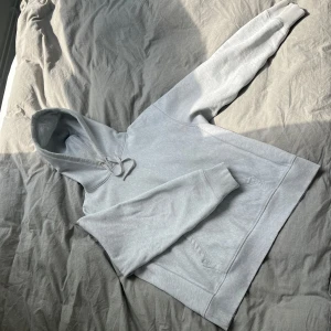 ARKET Ljusgrå hoodie - Säljer en enkel och stilren ljusgrå hoodie från ARKET med huva och dragsko. Tröjan är tjock i materialet och har en klassisk känguruficka framtill och ribbade muddar vid ärmslut och nederkant. Perfekt för en avslappnad look. Ordinarie pris 1600 kr.