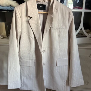 Beige randig kavaj från Bik Bok - Klassisk passform med två knappar framtill och tre fickor. Perfekt för en stilren look och enkel att matcha med olika outfits. Endast använd en gång och kommer inte till användning, pris kan diskuteras. 