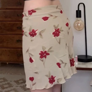 Beige kjol med röda blommor - Säljer en beige kjol med röda blommor och gröna blad. 💕