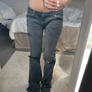 Svarta slitna jeans med bootcut - Säljer ett par svarta jeans med bootcut och slitna detaljer vid knäna. Har blivit sydda så de är lågmidjade, vilket kan synas om man är uppmärksam till låren men annars är stygnen inget man märker. 