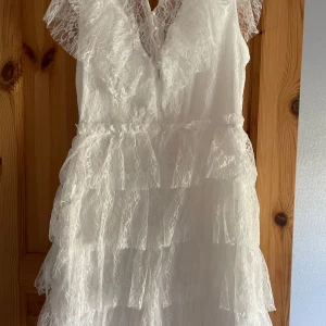 Vit spetsklänning med volanger från Bubbleroom - Superfin vit kortklänning från Bubbleroom med flera lager volanger och spetsdetaljer. Klänningen är ärmlös och har en v-ringad halsringning. Perfekt för studenten! (Endast testad men den var för stor för mig) 899kr ny!