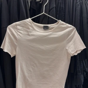 Vit t-shirt från Gina Tricot - En klassisk vit t-shirt från Gina Tricot med rund halsringning och korta ärmar. Perfekt basplagg i mjuk bomull som passar till allt. Enkel och stilren design.