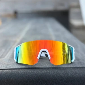 Sportiga solglasögon  - Säljer ett par sportiga solglasögon med stora, spegelblanka linser i orange, gult och rött. Bågarna är vita och designen är modern och kantig, perfekt för cool look😎