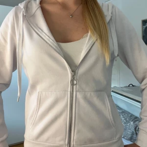 Vit zip hoodie - Säljer en klassisk vit hoodie från Fila med dragkedja framtill och huva med snören. Tröjan har två fickor på magen och ribbade muddar vid ärmslut och nederkant. Använd fåtal gånger och säljer då den inte kommer till användning💞