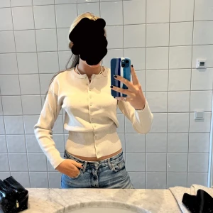 Beige ribbad kofta med knappar - Säljer en beige ribbad kofta med rund hals och knäppning framtill. Tröjan har långa ärmar och sitter tajt i midjan. 