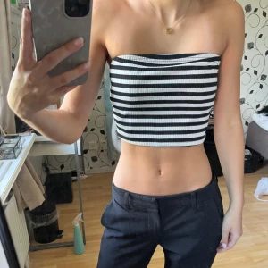 Randig bandeau tubtopp från SHEIN - Säljer en svartvit randig bandeau tubtopp från SHEIN i storlek XS. Toppen är ribbad och croppad, perfekt för varma dagar. Den är ärmlös och har en tight passform som sitter snyggt över bröstet. 