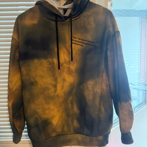 Tie-dye hoodie från SHEIN  - Hoodie från SHEIN i storlek S med tie-dye mönster i svart, grått och gult. Tröjan har huva med svarta snören och tryckt text på bröstet. Ganska tunn. 