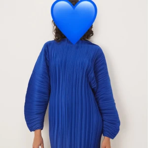 Blå plisserad kortklänning - Helt ny klänning! Köpte två storlekar och vill nu sälja den andra! Snygg blå kortklänning med plisserat tyg och ballongärmar. Klänningen har en loose passform och hög hals, vilket ger en cool och modern vibe. Perfekt för dig som vill sticka ut med en färgstark och trendig look💙💙