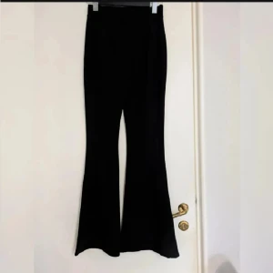 Tighta utsvängda byxor - Oanvända. Tighta, stretchiga, utsvängda byxor. Högmidjade med hällor, utan fickor. 