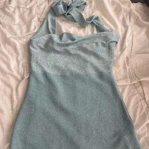 Glittrig ljusblå kortklänning Shein - Supersöt ljusblå kortklänning från Shein med glittrigt tyg och halterneck som knyts i nacken har faktiskt haft den på och den fungerar även som en topp för jag är 175 så den är kort på mig men den går även att styla som topp. Sitter figurnära och har en snygg, enkel design som verkligen poppar. Perfekt för dig som vill sticka ut med lite extra shine. Bättre bilder finns om de behövs den är superfin på en. 