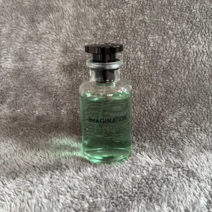 Louis Vuitton Imagination Parfym 100ml - Lyxig parfym från Louis Vuitton, Imagination Eau de Parfum.. Kommer i elegant vit kartong och cylinderförpackning med guld- och svart text. Volym: 100 ml.