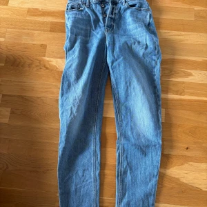  blåa high waist jeans - Snygga blå jeans med hög midja och raka ben. Klassisk femficksmodell med knäppning framtill. Använda några gånger men inga defekter, eller slitningar. W28 L30. Läs gärna bio💕