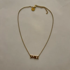 Sophie by Sophie halsband SMILE - Halsband från Sophie by Sophie i guldton med kedja och ett hängsmycke. Halsbandet är i äkta silver (stämplat 925) och har justerbar längd. ✨ Tyvärr finns inte originalförpackningen kvar, men halsbandet skickas i en annan smyckespåse.