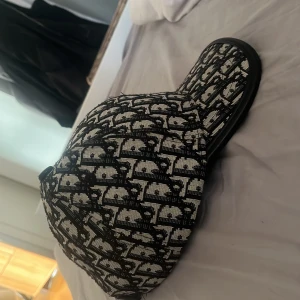Svartvit keps med mönster - Snygg keps i svart och vitt med ett grafiskt, rutigt mönster från Christian Dior. Kepsen är äkta och är använd ett fåtal gånger 