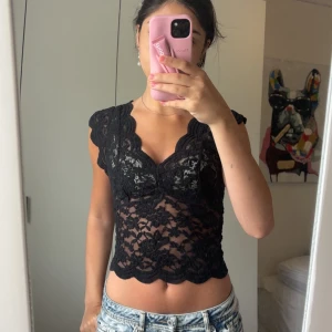 Svart spetsblus med v-ringning bak och fram - Jätte fin topp, i jätte bra skick. Är öppen i ryggen också. Storlek S men kan passa även xs då den är stretchig. Perfekt till fest!