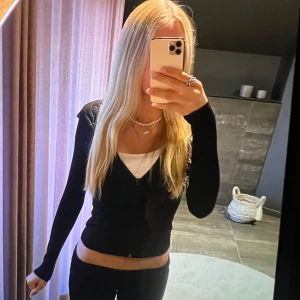 Svart tunn kofta - Svart hoodie med dragkedja framtill och långa ärmar. Snygg och enkel modell som sitter tight och har en klassisk huva. Perfekt att slänga på sig över ett linne eller t-shirt för en chill look.