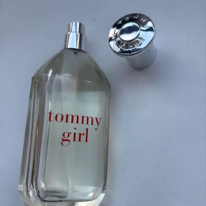 Tommy Girl parfym från Tommy Hilfiger - Fräsch och klassisk Tommy Girl parfym från Tommy Hilfiger. Flaskan är transparent med röd text och har en silvrig metallkork. Doften är lätt och ungdomlig, perfekt för dig som gillar en ren och fräsch känsla. Snygg och stilren design som passar på hyllan.