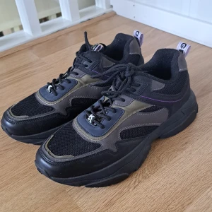 Chunky sneakers från Kurt Geiger - Chunky sneakers från Kurt Geiger i svart med lila, gröna och blå detaljer. Ovandel i mesh och syntet med coola paneler och snörning. Grov platt sula för extra attityd. Perfekta för dig som gillar streetstyle och vill sticka ut. Kommer tyvärr utan box💕