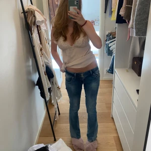 Blå bootcut jeans från LTB - Snygga blå bootcut jeans från LTB med låg midja och klassiska fem fickor. Jeansen har en ljus tvätt och coola detaljer på bakfickorna samt läderpatch med logga. Perfekta för dig som gillar en avslappnad men trendig look. Den är insydd från förra ägarens midjan och även så att den ska bli bootcut. Jag visar i bilderna💞längd 32 och midja cirka 36 (CM)