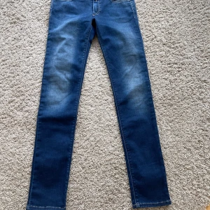 Blå jeans från Replay - Snygga blå jeans från Replay med klassisk femficksdesign och coola detaljer på bakfickorna. Jeansen har en bra passform och är tillverkade i stretchigt denim för extra komfort. Perfekta för dig som gillar en stilren och modern look.